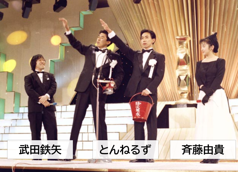第11日本アカデミー賞授賞式の一場面、中央にとんねるず、両脇に武田鉄矢さんと斉藤由貴が立っています。