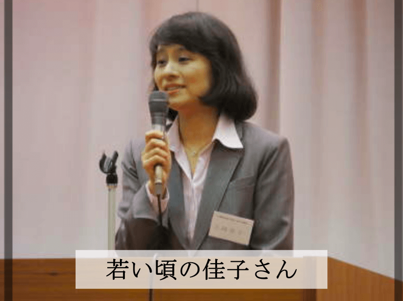 若い頃の佳子さんがマイクを片手に講演をしています。